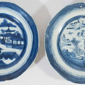 May include: Two blue and white porcelain plates with a Chinese landscape design. The plates have a scalloped edge and a white center with a blue border.