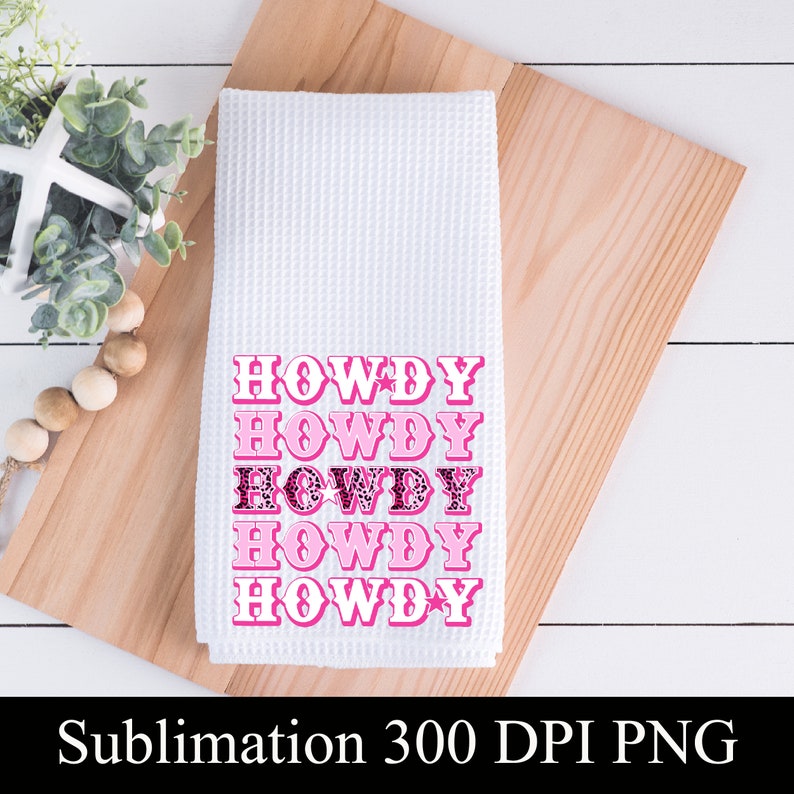 Pu&ograve; includere: Un asciugamano da cucina bianco con la parola "HOWDY" ripetuta cinque volte in lettere rosa. Le lettere sono contornate di nero e hanno un motivo leopardato rosa e nero. L'asciugamano &egrave; su una superficie di legno.