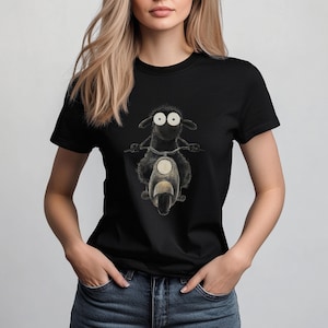 May include: A black t-shirt with a graphic of a black sheep riding a scooter. The sheep has large white eyes.