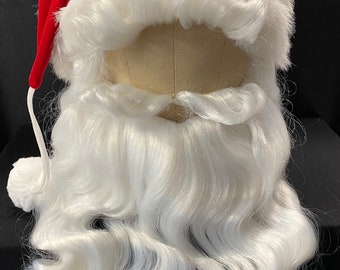 Può includere: Un set di costumi di Babbo Natale con un cappello di velluto rosso con un pompon bianco e una lunga barba bianca fluente. La barba e l'orlo del cappello sono realizzati in materiale bianco e soffice, creando un look festivo.