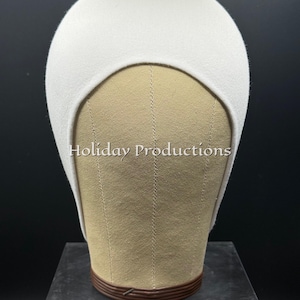May include: A white, close-fitting cap, likely a wig cap, is displayed on a mannequin head. The cap is made of a soft, felt-like material. The text "Holiday Productions" is visible on the mannequin.