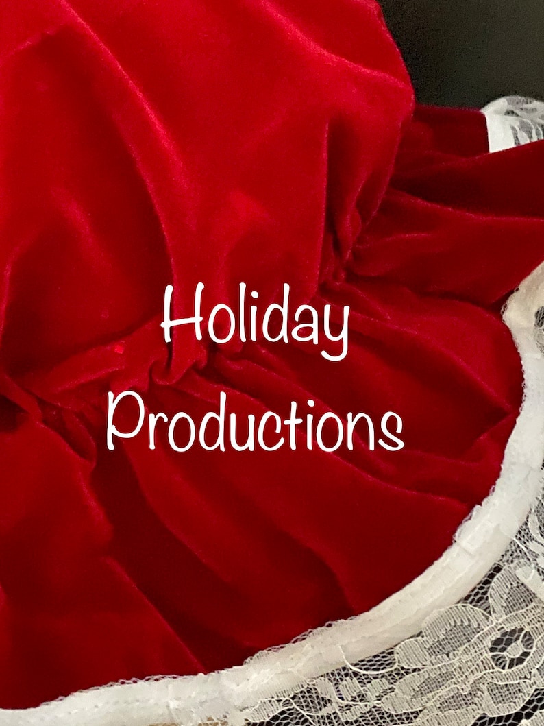 Pu&ograve; includere: Primo piano di un tessuto di velluto rosso con il testo "Holiday Productions" in bianco. Il tessuto ha un bordo a balze con finiture in pizzo bianco. L'immagine &egrave; ben illuminata, evidenziando la trama e il colore del materiale.