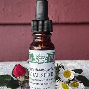 May include: A brown glass bottle with a black dropper top and a white label that reads "Knight Moon Apothecary Facial Serum". The label also says "the appearance of wrinkles more youthful complexion" and "NET WT. 1/2 OZ."
