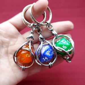 May include: Three silver keychains with a dice charm. Each keychain has a different colored dice: orange, blue, and green.