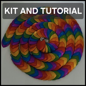 Peut inclure: Une bande de cotte de mailles enroulée composée de pièces métalliques en forme d'écailles superposées dans un dégradé arc-en-ciel de rouge, orange, jaune, vert, bleu et violet. Le texte KIT AND TUTORIAL apparaît en blanc sur fond gris.