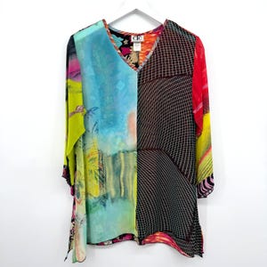 May include: A long-sleeve tunic featuring a V-neckline and a split-panel design. The left side displays a vibrant blue, yellow, and green abstract print, while the right side features a black and white grid pattern. The label reads CIC.