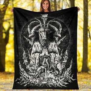 May include: Black and white fleece blanket with a graphic of a three-headed goat with red eyes, horns, and a crown. The goat is surrounded by skulls and other demonic imagery.