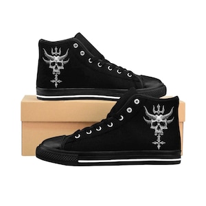 Puede incluir: Zapatillas de lona negras de caña alta con un gráfico blanco de calavera y tridente. Las zapatillas tienen una franja blanca alrededor de la suela.