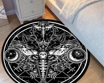 May include: Black and white round rug with a large moth design in the center. The moth has a skull head and is surrounded by a circle of roses, stars, and eyes. The rug has a geometric pattern around the edge.