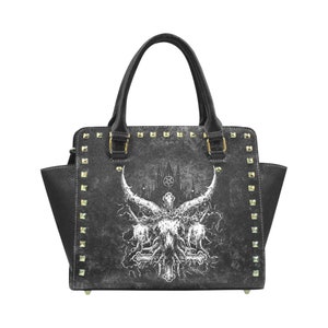 May include: Black handbag with a gothic design featuring a white skull with horns and a cross. The bag has gold studs around the edges.
