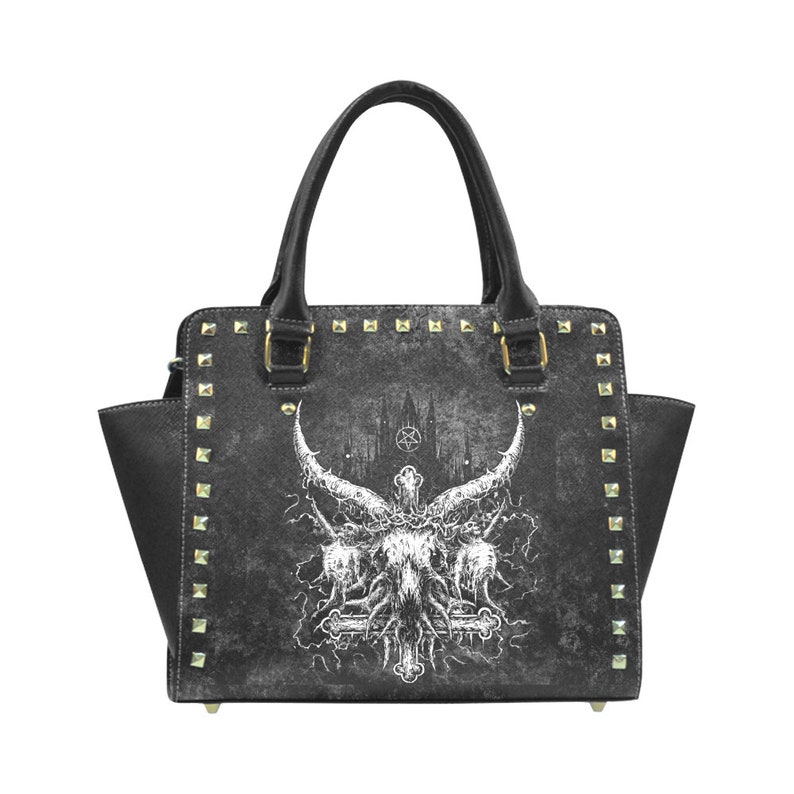 May include: Black handbag with a gothic design featuring a white skull with horns and a cross. The bag has gold studs around the edges.