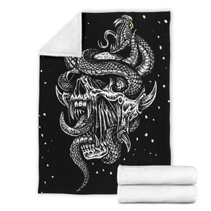 May include: Black and white illustration of a skull with a snake wrapped around it. The skull has a large, open mouth with sharp teeth and a long, pointed tongue. The snake has a detailed, scaly texture and is coiled around the skull's head. The background is black with white dots.