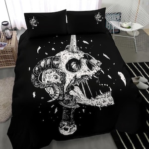 May include: Black and white bedding set featuring a skull with horns pierced by a dagger. The skull has a detailed design and is set against a black background.