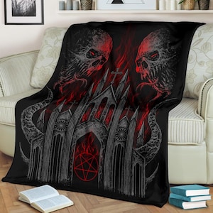 Può includere: Coperta in stile gotico nero e rosso con due teschi demoniaci con fiamme e una chiesa sullo sfondo. La chiesa ha un pentagramma alla base.