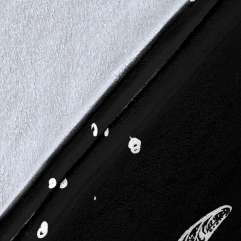 May include: A black fabric with a white pattern of small circles and a larger, abstract shape. The fabric is folded in half, with the white side facing up.
