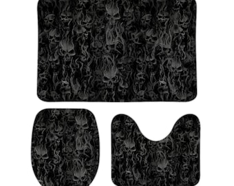 Pode incluir: Um conjunto de três tapetes de banheiro com um padrão de caveira e chamas em preto e branco. O conjunto inclui um tapete de banheiro grande, uma tampa de assento de vaso sanitário e um tapete de contorno menor.