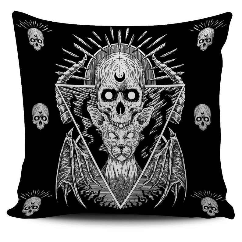 Puede incluir: Coj&iacute;n cuadrado negro con un dise&ntilde;o g&oacute;tico. El coj&iacute;n presenta una ilustraci&oacute;n central de una calavera con una luna creciente, una criatura felina y alas de murci&eacute;lago, todo dentro de un tri&aacute;ngulo. Peque&ntilde;os motivos de calaveras est&aacute;n dispersos sobre el fondo negro.