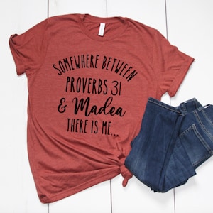 May include: A rust-colored t-shirt with the text "Somewhere between Proverbs 31 & Madea there is me..." printed in black.
