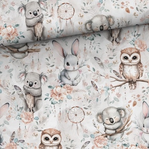 Può includere: Un tessuto bianco con un motivo ripetitivo di koala, gufi, conigli, acchiappasogni, piume e fiori in tonalità di rosa, blu e verde.