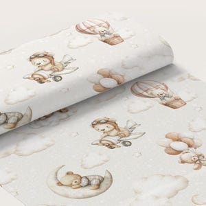 Peut inclure: Un tissu beige clair avec un motif répétitif d'ours en peluche style aquarelle. Les ours sont représentés volant dans de petits avions, flottant dans des montgolfières, tenant des grappes de ballons et dormant sur des croissants de lune.