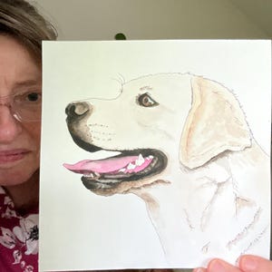 May include: Watercolor painting of a golden Labrador Retriever dog. The dog is depicted in profile, with a pink tongue, open mouth, and detailed fur. The artwork is on a white background, showcasing the dog's features.