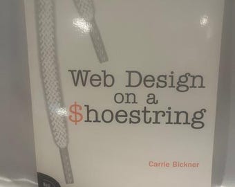 May include: A book titled "Web Design on a Shoestring" by Carrie Bickner. The cover is white with a graphic of a shoelace and the text in black and orange. The book is part of the "New Riders" series.