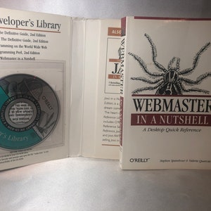 Peut inclure: Un livre blanc avec une araignée brune sur la couverture. Le titre est "Webmaster in a Nutshell: A Desktop Quick Reference" par O'Reilly.