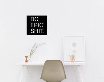 May include: Black and white motivational poster with the text "DO EPIC SHIT." hanging on a white wall above a white desk with a chair, a potted plant, and a candle.