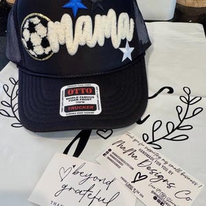 May include: Black trucker hat with a white "mama" design, blue and black star accents, and a soccer ball patch. Includes a tag that says "OTTO TRUCKER". Two cards read "beyond grateful" and "Thank you for supporting my small business!"