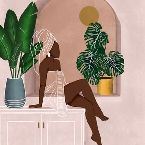 May include: A woman with dark skin sits on a white cabinet with a white towel wrapped around her. She has a white turban on her head and a gold earring. There are two plants in the background, one with green leaves and the other with large, green leaves. The background is a light pink color.