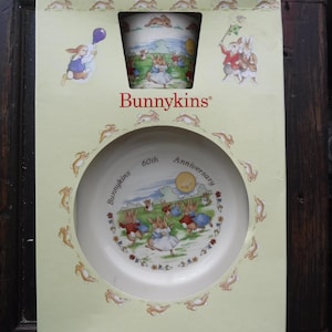 May include: A boxed Bunnykins 60th Anniversary set, including a mug and a bowl. The set features illustrations of rabbits in various outfits. The box is light green with the Bunnykins logo and rabbit illustrations.