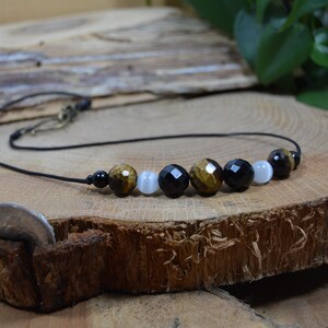 May include: A black cord necklace with tiger's eye, black onyx, and white moonstone beads.
