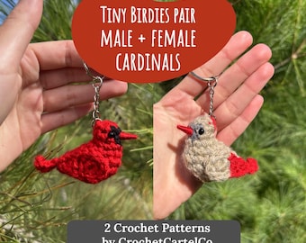 May include: Two crochet cardinal keychains, one red and one gray, are held up against a green background. The red cardinal has a black beak, and the gray cardinal has a red beak. Text reads "Tiny Birdies Pair Male + Female Cardinals".