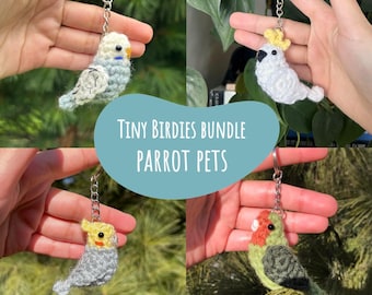 Op de afbeelding: Een collage van vier gehaakte vogel sleutelhangers. De vogels zijn in verschillende kleuren, waaronder blauw, wit, grijs, geel, oranje en groen. De tekst "TINY BIRDIES BUNDLE PARROT PETS" staat in het midden. De tekst "4 Crochet Patterns by CrochetCartelCo" staat onderaan.