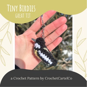 Może przedstawiać: Wzór na szydełku na brelok w kształcie sikory bogatki. Ptak jest czarny, biały i żółty i jest szydełkowany w realistycznym stylu. Brelok jest przymocowany do srebrnego łańcuszka.