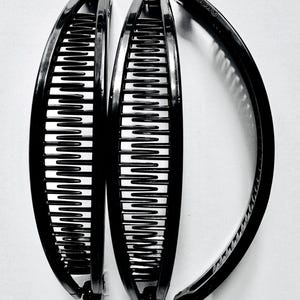 May include: Three black plastic hair clips. The clips are curved and have a comb-like design.