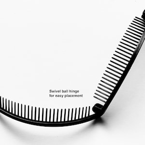 Puede incluir: Un peine para el cabello negro con una bisagra de r&oacute;tula giratoria para una f&aacute;cil colocaci&oacute;n. El peine tiene dos secciones curvas con dientes, conectadas por una bisagra. El texto "Swivel ball hinge for easy placement" es visible.