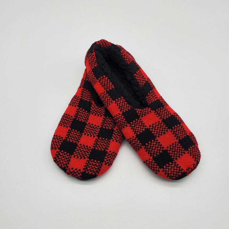 May include: A pair of red and black plaid slipper socks. The socks are made of a soft, comfortable material and have a fuzzy lining.