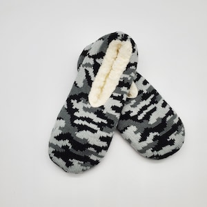 May include: A pair of black and gray camouflage slipper socks with a white fleece lining.