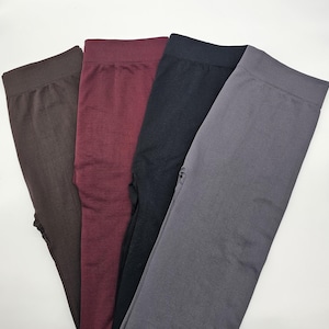 May include: A set of four pairs of leggings featuring a high-waisted design with a wide, ribbed waistband. The leggings are presented in four distinct solid colors: dark brown, deep burgundy, black, and a medium charcoal gray.