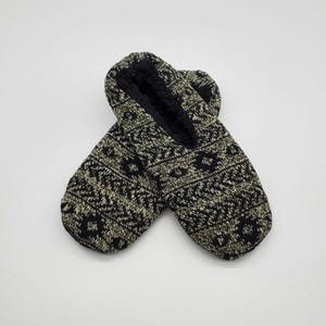 May include: A pair of black and white patterned slipper socks. The socks have a fuzzy lining and are made of a soft, knitted fabric.