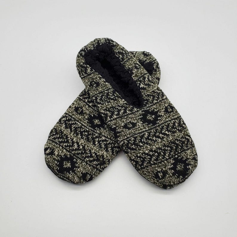 May include: A pair of black and white patterned slipper socks. The socks have a fuzzy lining and are made of a soft, knitted fabric.