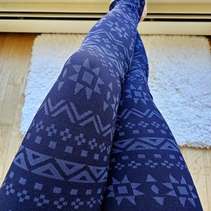 May include: A pair of dark blue leggings with a geometric pattern in a lighter shade of blue. The pattern is reminiscent of a traditional Scandinavian design.