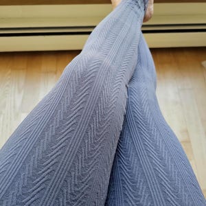 May include: Close-up of grey leggings with a textured chevron pattern. The leggings are made of a soft material and are designed for comfort and style. The leggings are a solid colour and are suitable for various activities.