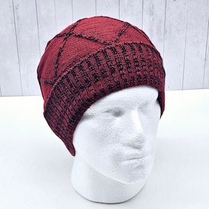May include: A red and black knit beanie with a diamond pattern. The beanie is on a white mannequin head.