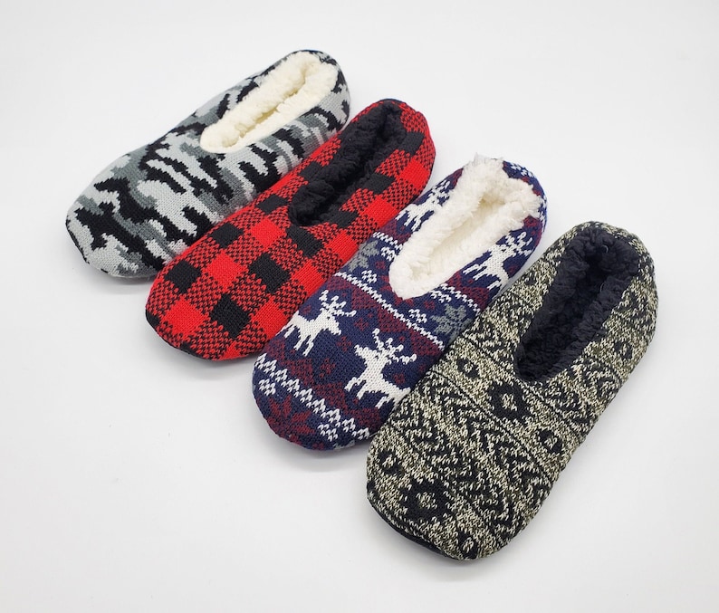 May include: Four pairs of cozy slipper socks with different patterns. The socks are made of a soft, fuzzy material and have a warm, comfortable feel. The patterns include a camouflage design, a red and black plaid design, a blue and white reindeer design, and a black and gold geometric design.