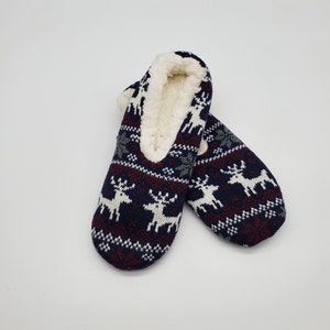 May include: Pair of blue, red, and white slipper socks with a reindeer pattern. The socks are lined with white faux fur.