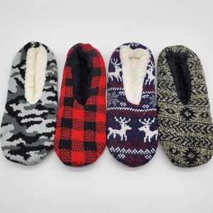May include: Four pairs of cozy slipper socks with different patterns. One pair is gray with a camouflage pattern, one pair is red and black plaid, one pair is blue with a white reindeer pattern, and one pair is green with a geometric pattern.