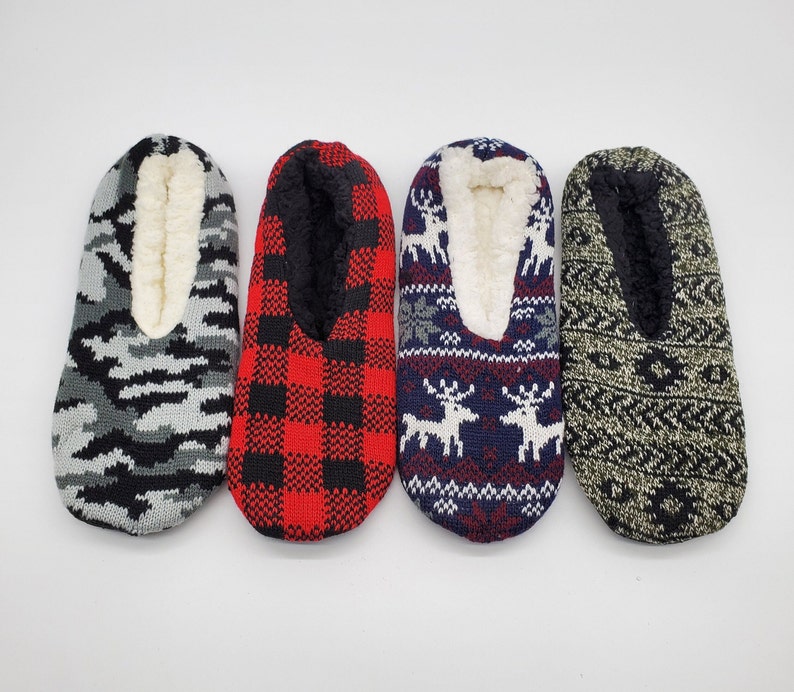 May include: Four pairs of cozy slipper socks with different patterns. One pair is gray with a camouflage pattern, one pair is red and black plaid, one pair is blue with a white reindeer pattern, and one pair is green with a geometric pattern.