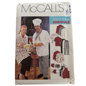 May include: A McCall's sewing pattern envelope labeled Uniform Essentials M2233 XL. The front displays illustrations of chef uniforms including white jackets, checkered pants, aprons, and hats, alongside a photo of two people wearing these garments.